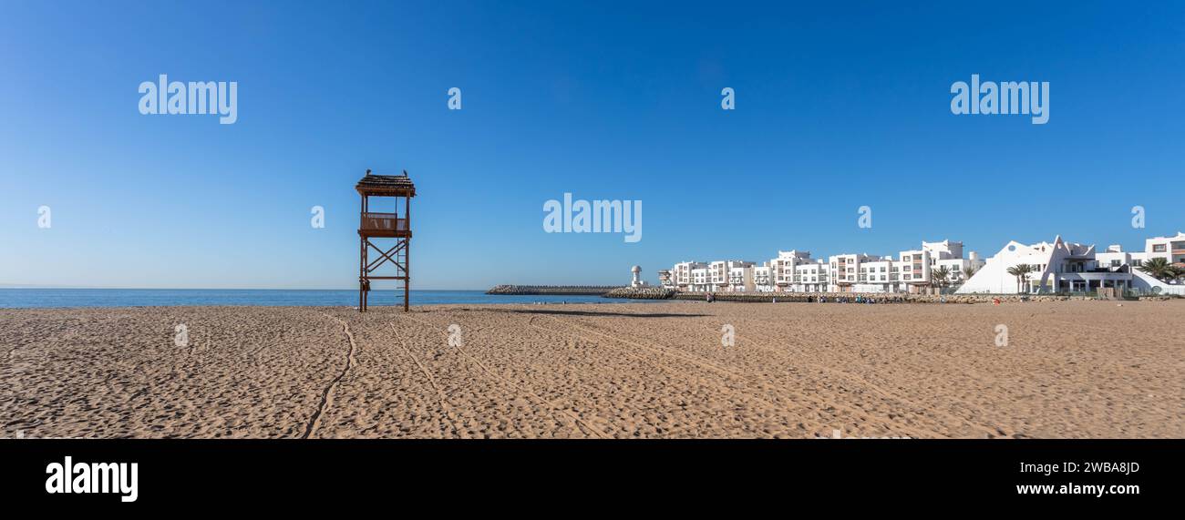 Wide-angle view of Agadir's sandy beach and the wooden lifeguard tower, with Atlantic Ocean and waterfront buildings. Agadir, Morocco, North Africa Stock Photo