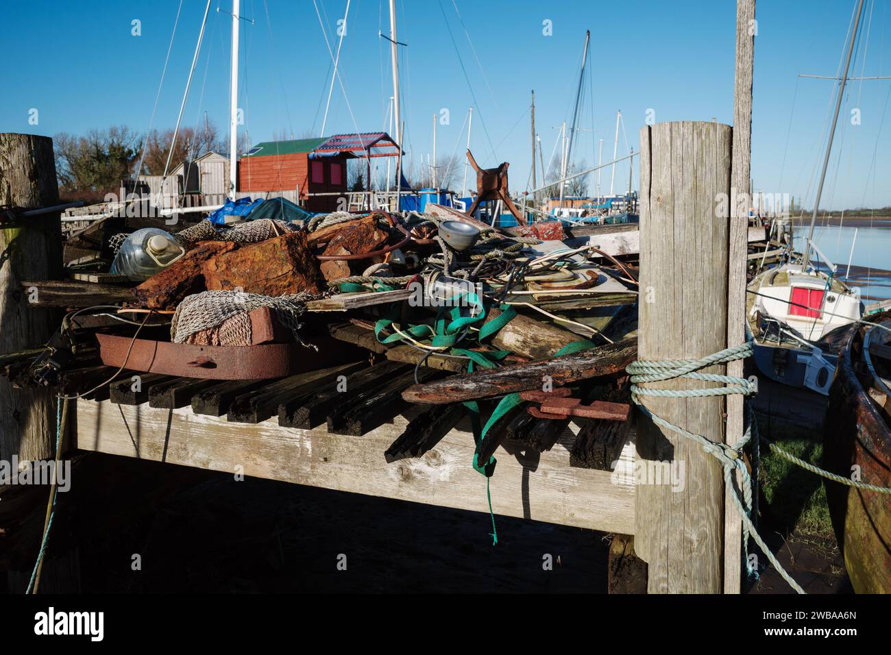 Wooden boat mooring with piles of old junk on the jetty Skippool creek Lancashire UK Stock Photo