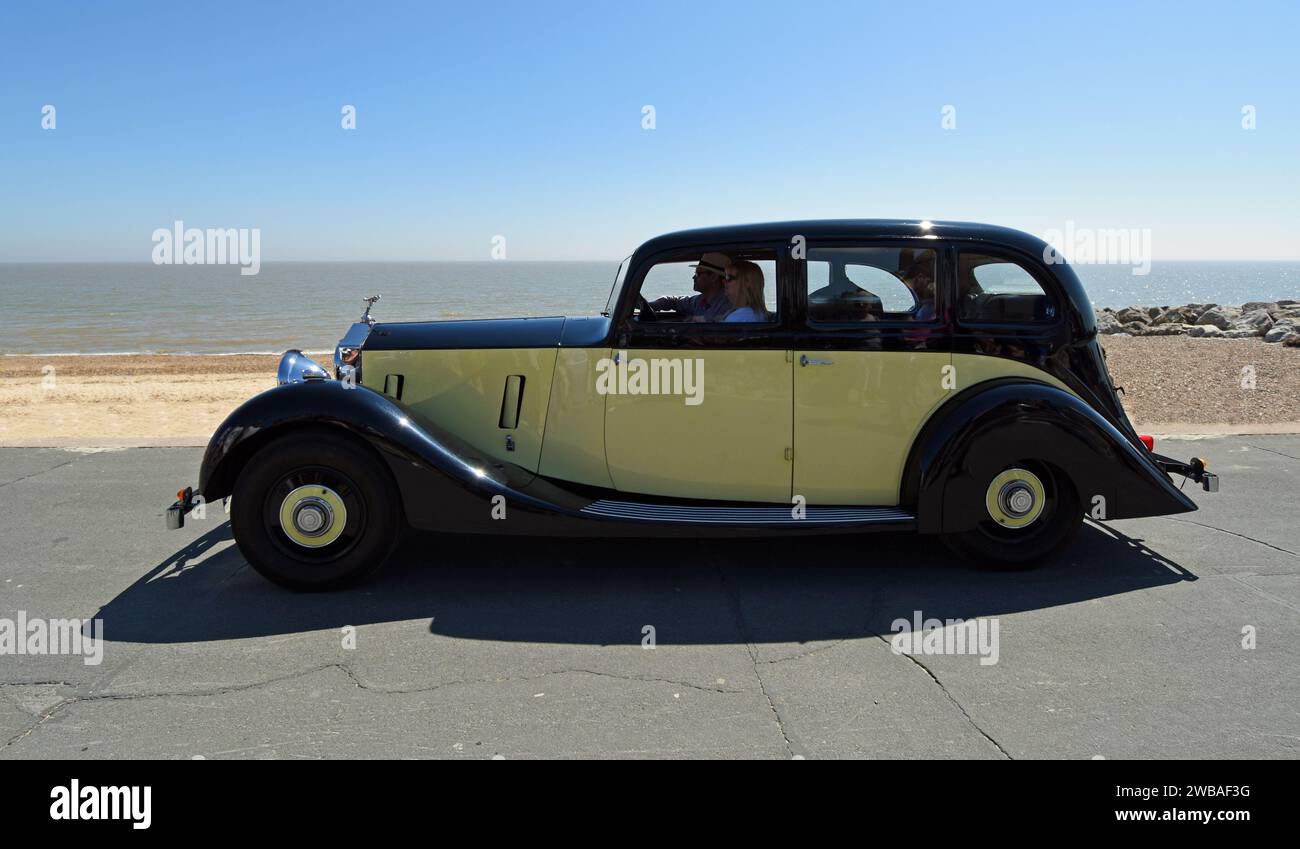 Vintage  Rolls Royce Motor Car being driven on seafront promenade beach and sea in background Stock Photo