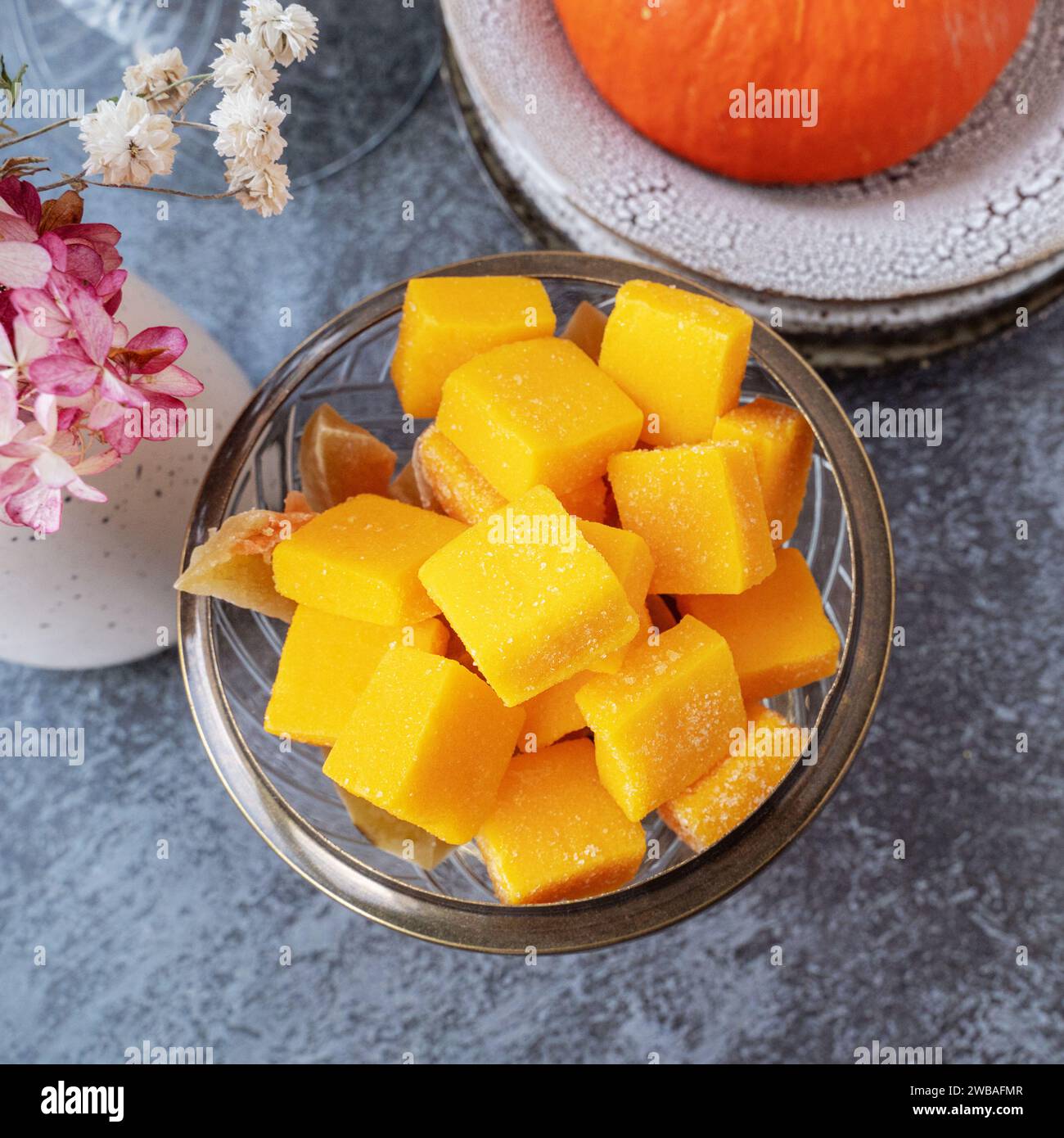 Jellied candy, candied pumpkin in a glass candy bowl. Homemade pumpkin candies close-up. Stock Photo