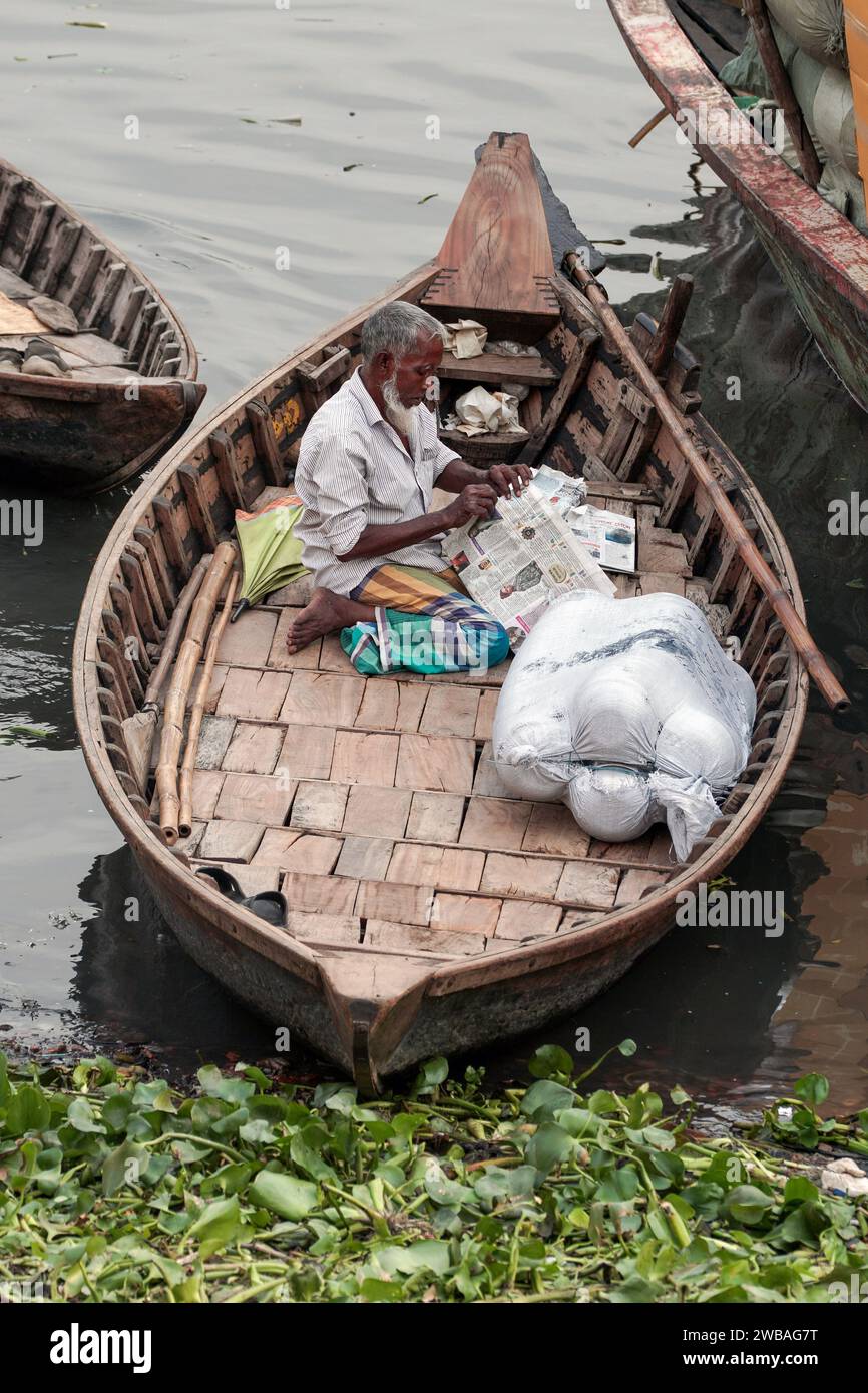 A ferryman waiting for clients in his wooden boat at the Buriganga River in Dhaka, Bangladesh Stock Photo