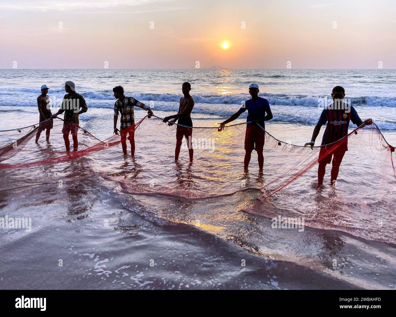 Fishermen on the beach at Benaulim in Goa, India, pull their nets ashore and sort their catch Stock Photo