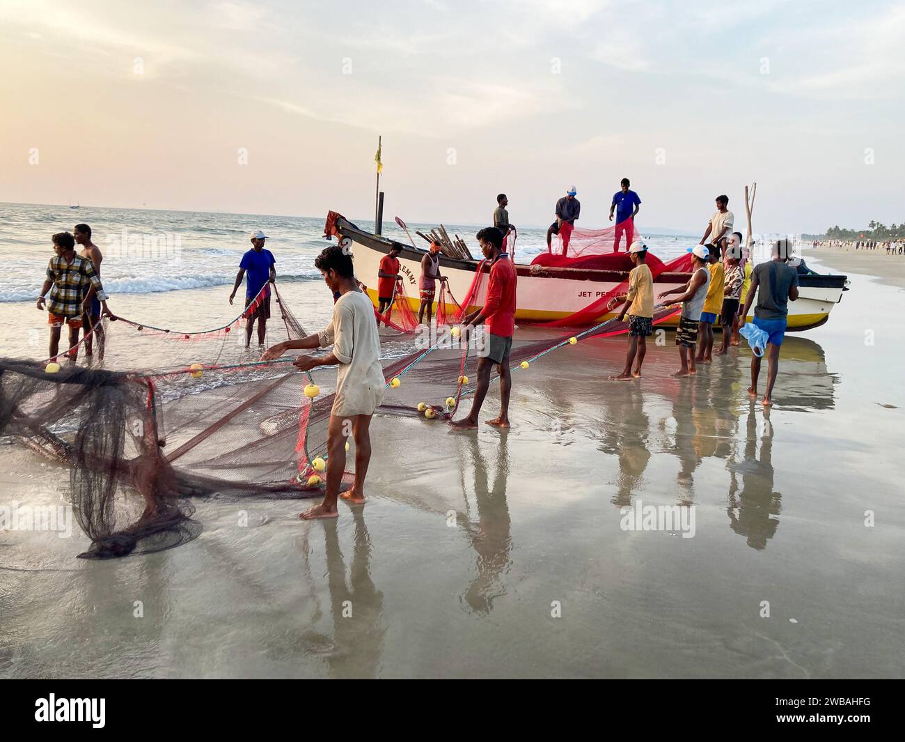 Fishermen on the beach at Benaulim in Goa, India, pull their nets ashore and sort their catch Stock Photo