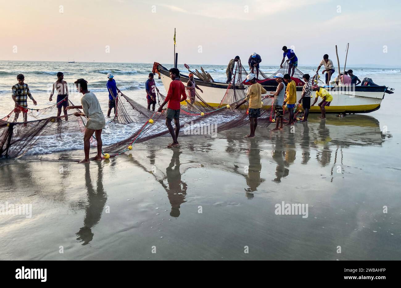 Fishermen on the beach at Benaulim in Goa, India, pull their nets ashore and sort their catch Stock Photo