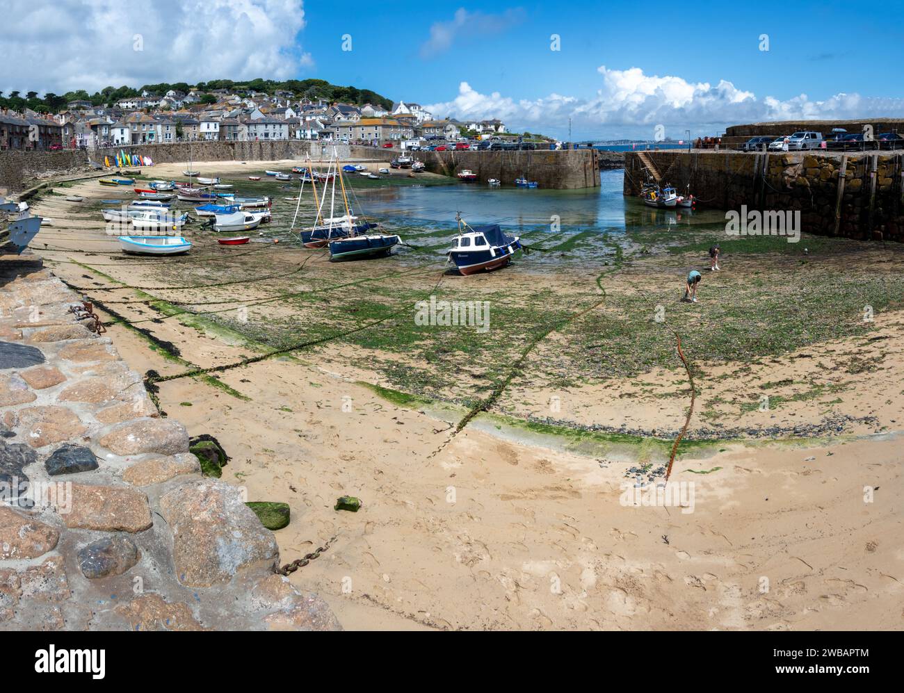 Small boats aground in Mousehole harbour at low tide Cornwall England Stock Photo