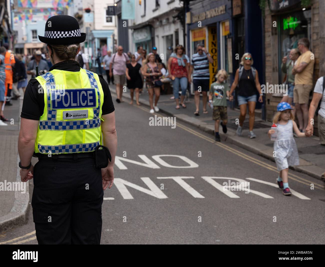 Back of female police officer in Hi vis on street with lots of people Falmouth Cornwall England Stock Photo