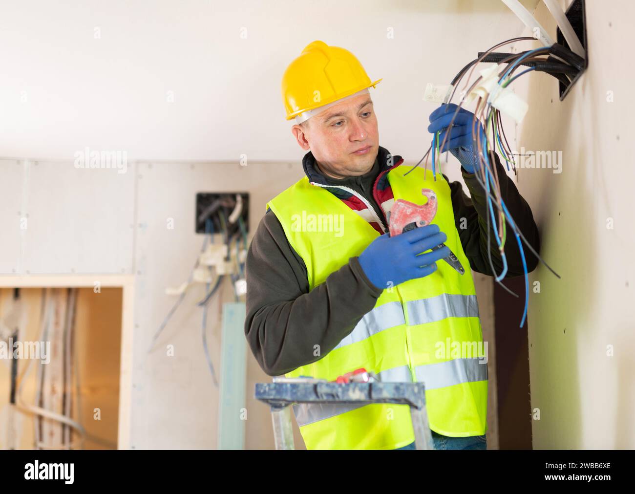 Experienced electrician laying electric wires in building under ...