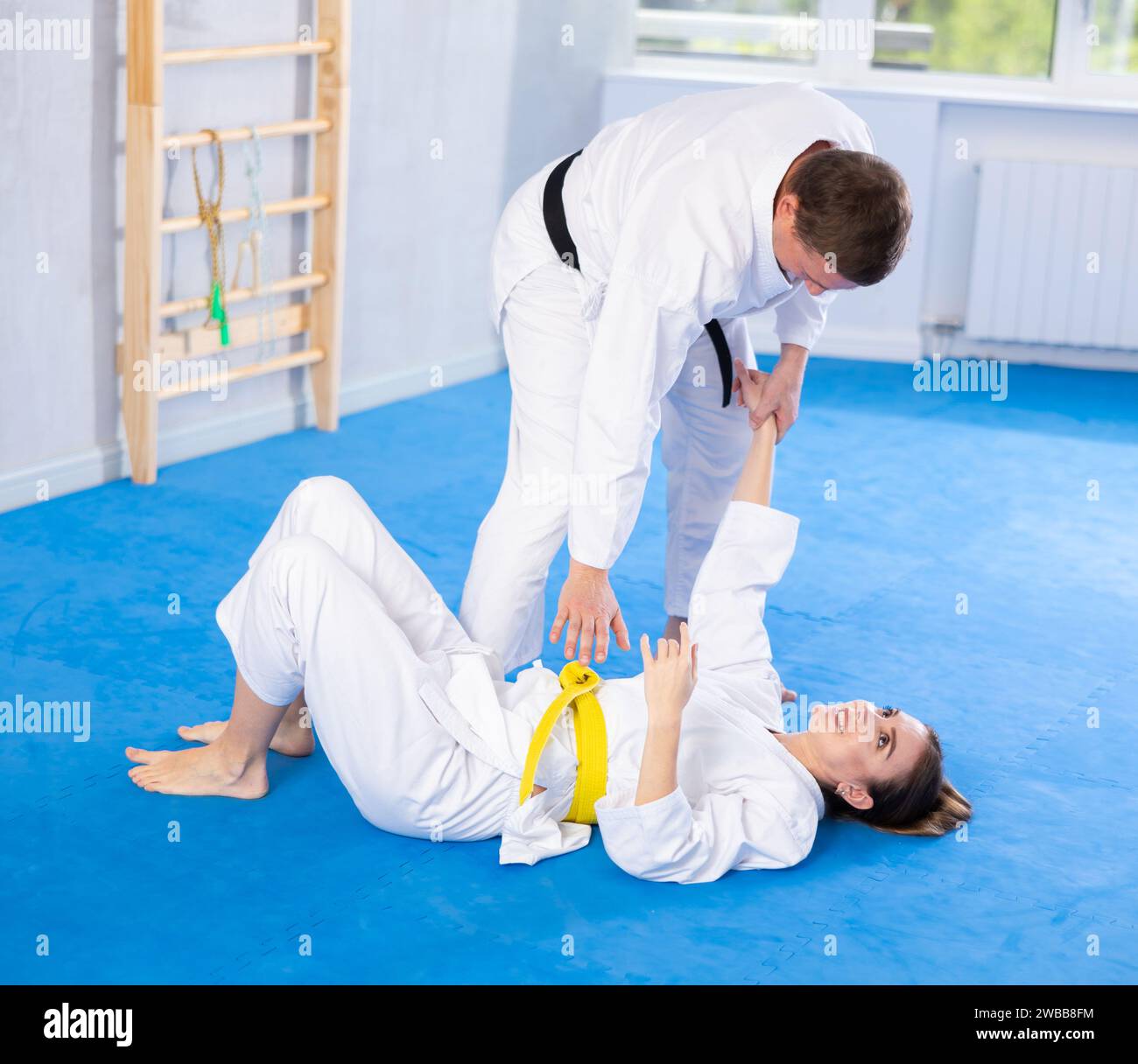 Coach teaches young woman techniques for wrestling and throwing on