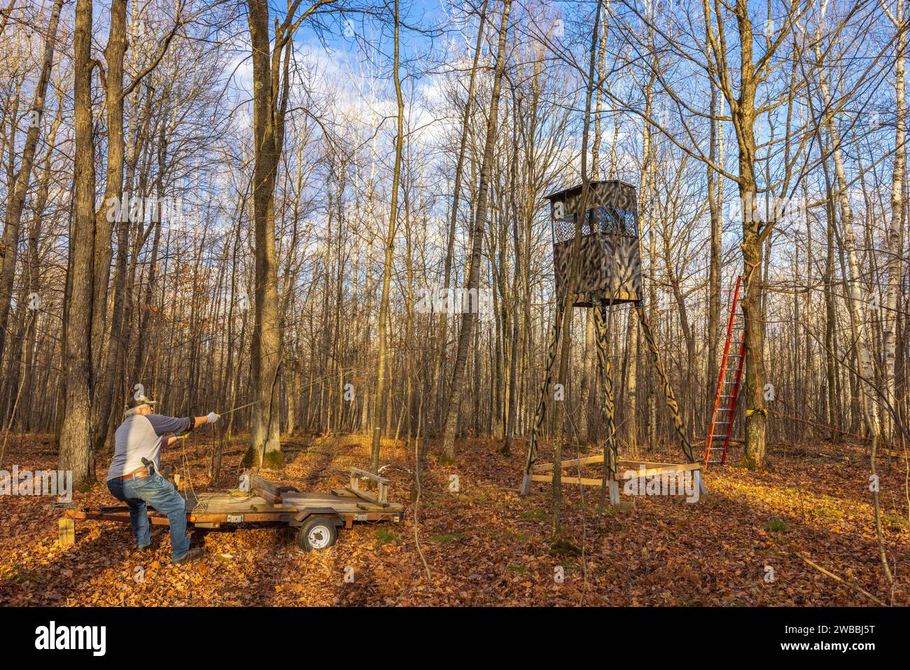 Man preventing a homemade deer hunting stand from toppling over as it's