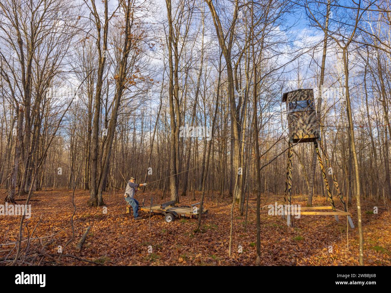 Man preventing a homemade deer hunting stand from toppling over as it's