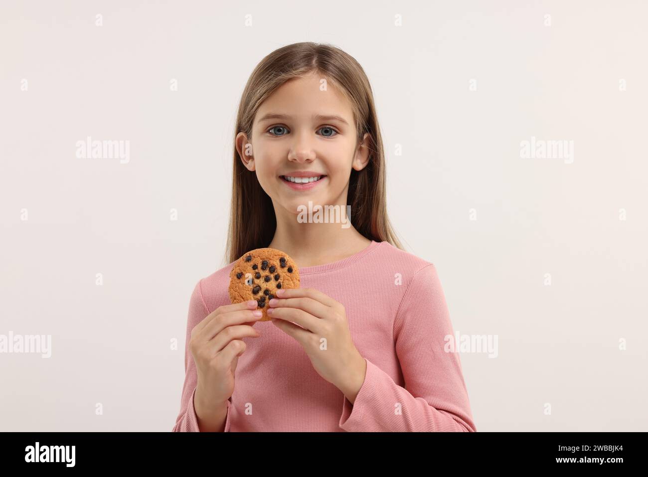 Cute girl with chocolate chip cookie on white background Stock Photo ...