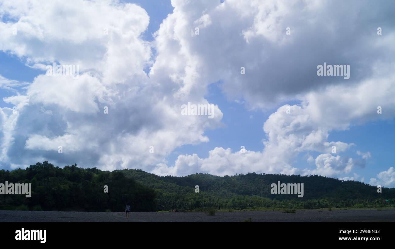 A photograph of a mountainous stony shore and cloudy sky in Tinapuay, Banga, Aklan, Philippines. Stock Photo