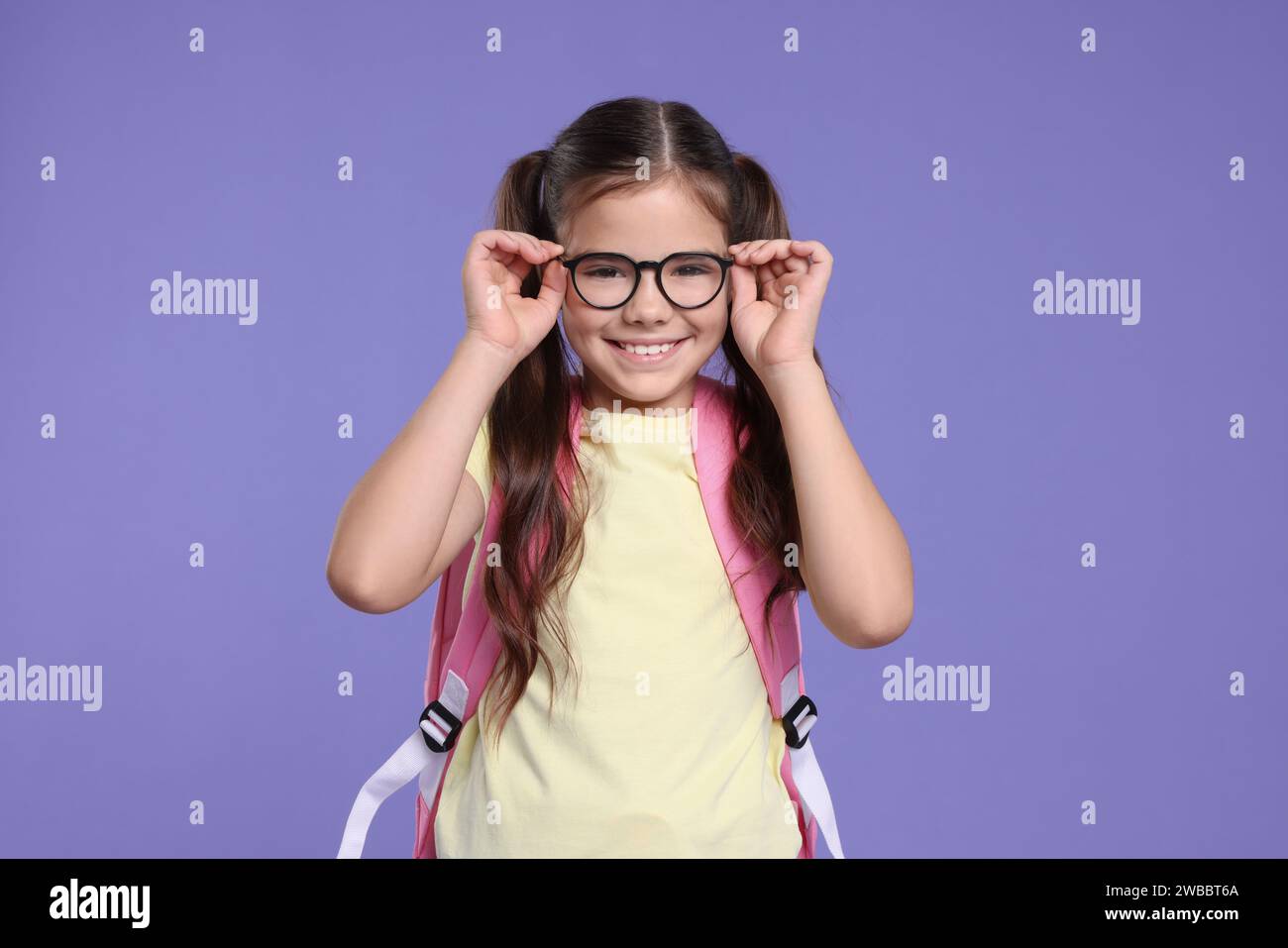 Cute schoolgirl in glasses with backpack on violet background Stock ...