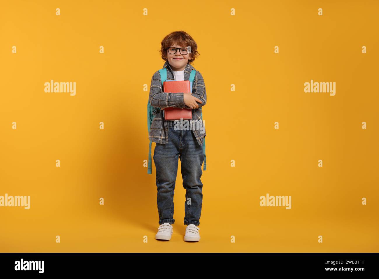 Happy schoolboy with backpack and books on orange background Stock ...