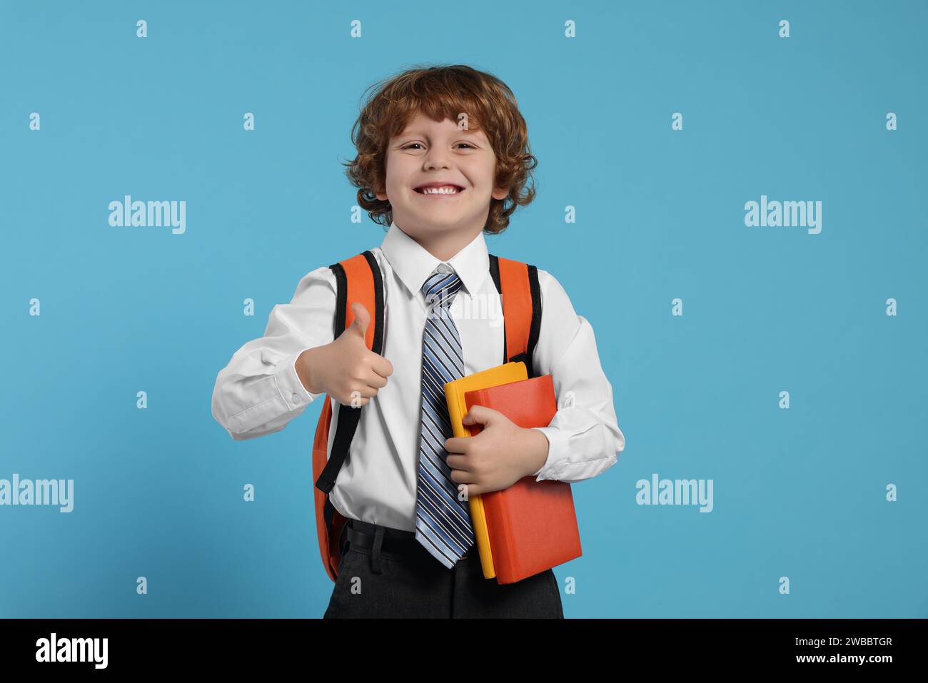 Happy schoolboy with backpack and books showing thumb up gesture on ...