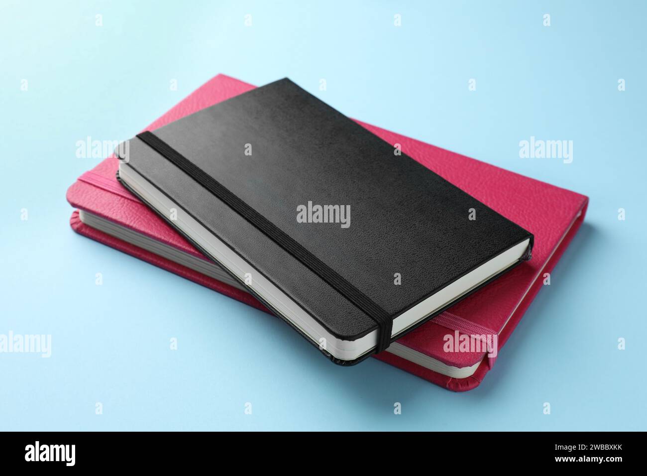Black and pink notebooks on light blue background Stock Photo