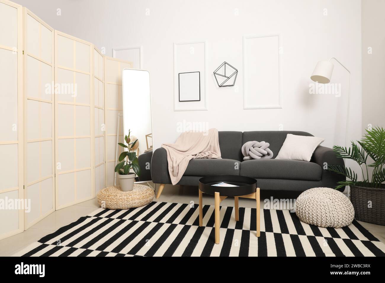 Interior of light living room with grey sofa, mirror and coffee table ...