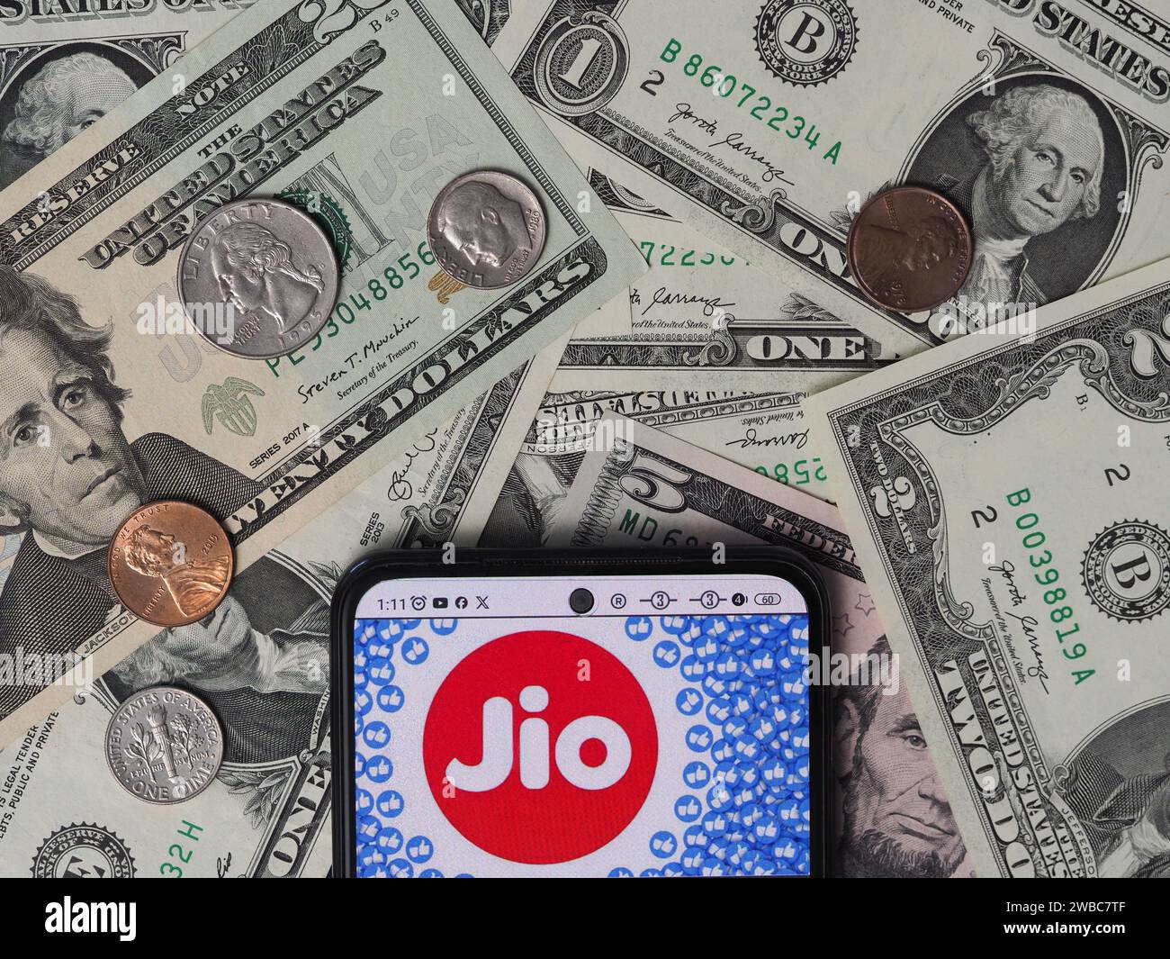 Germany. 10th Jan, 2024. In this photo illustration, a Reliance Jio Infocomm Limited logo seen displayed on a smartphone with United States Dollar notes and coins in the background. Credit: SOPA Images Limited/Alamy Live News Stock Photo