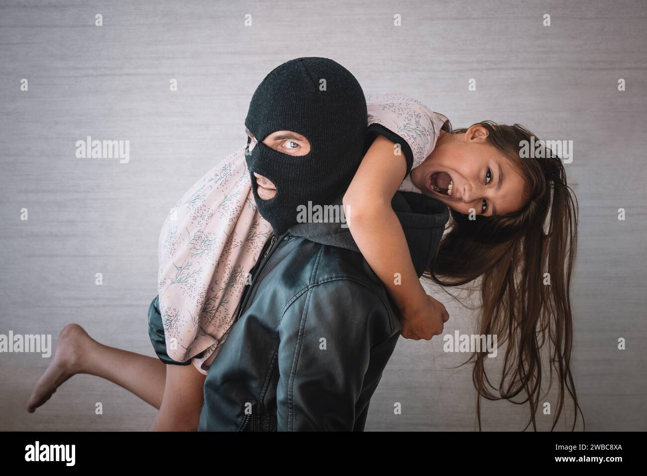 Terrorist and scared little hostage on white background. The concept of