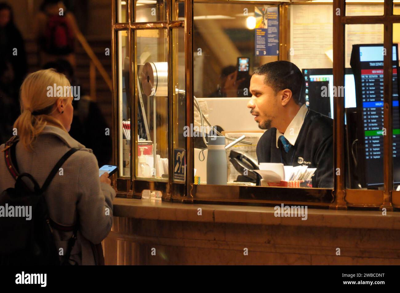 New York, United States. 09th Jan, 2024. A person inside an information booth, right, talks to a customer in the main concourse of Grand Central Terminal in midtown Manhattan, New York City. Credit: SOPA Images Limited/Alamy Live News Stock Photo