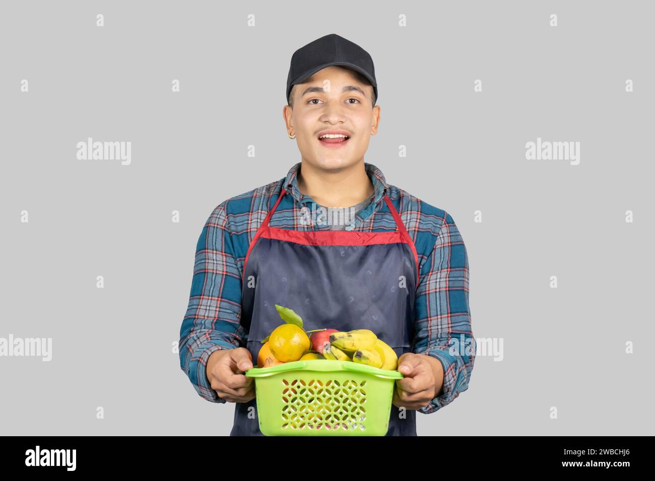 Young Asian Muscular and Healthy Male Farmer Promoting Organic Lifestyle with Fruit and Fruit Basket Stock Photo