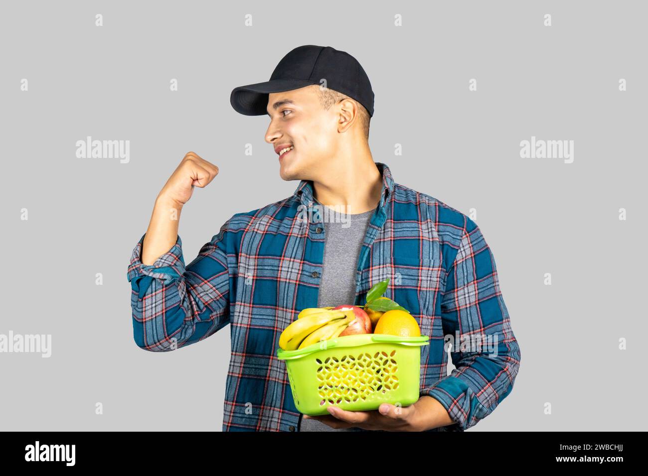 Young Asian Muscular and Healthy Male Farmer Promoting Organic Lifestyle with Fruit and Fruit Basket Stock Photo