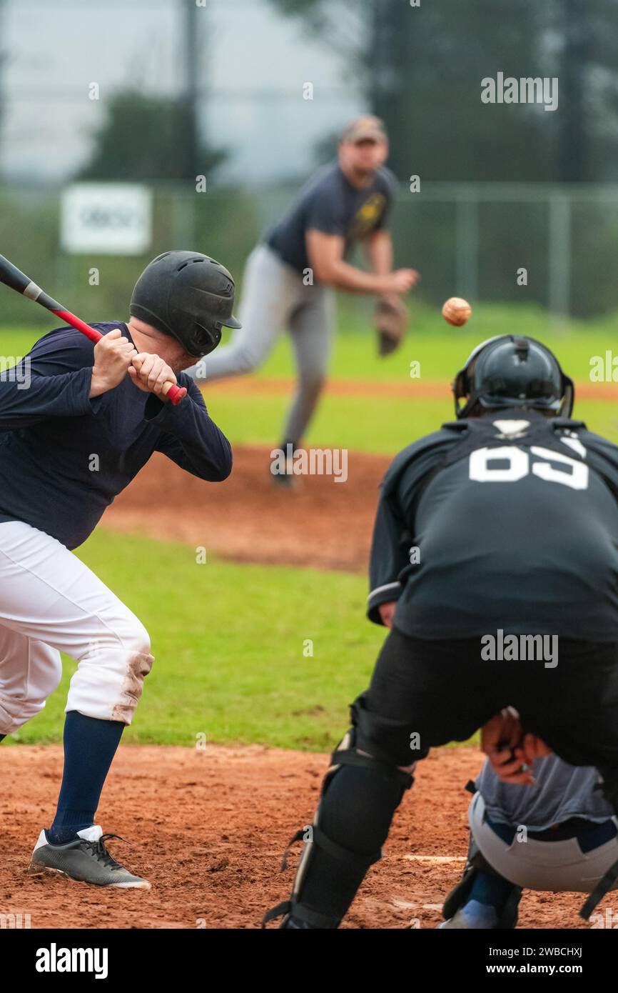 Men playing baseball game. Batter getting ready to hit a pitch during ballgame on a baseball diamond, field. Stock Photo