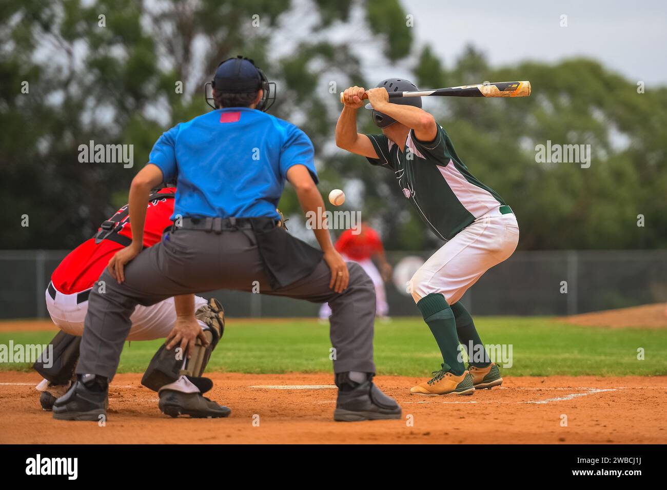 Men playing baseball game. Batter getting ready to hit a pitch during ballgame on a baseball diamond, field. Stock Photo