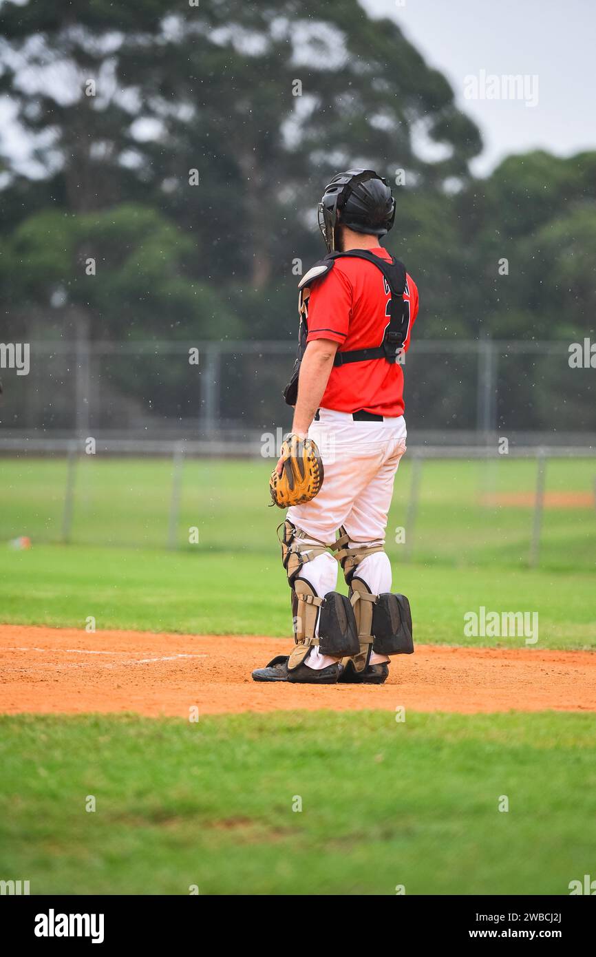 Baseball game, catcher is standing up and watching the play during the