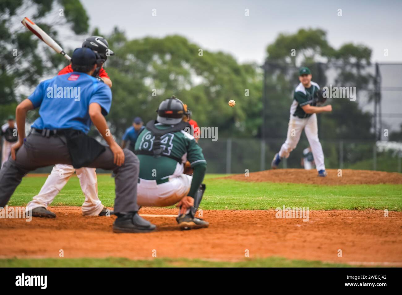 Men playing baseball game. Batter getting ready to hit a pitch during ballgame on a baseball diamond, field. Stock Photo