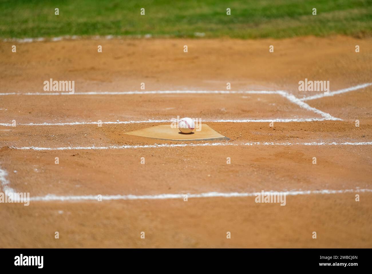 Baseball game, baseball ball sitting on the home plate, base, during the baseball game. Stock Photo