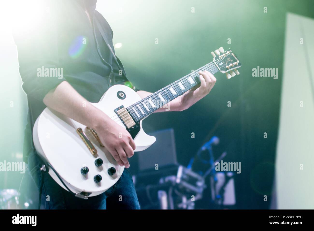 A rock guitarist takes center stage, fingers dancing on the guitar, while the band blurs behind, adding a mysterious rock vibe. Stock Photo