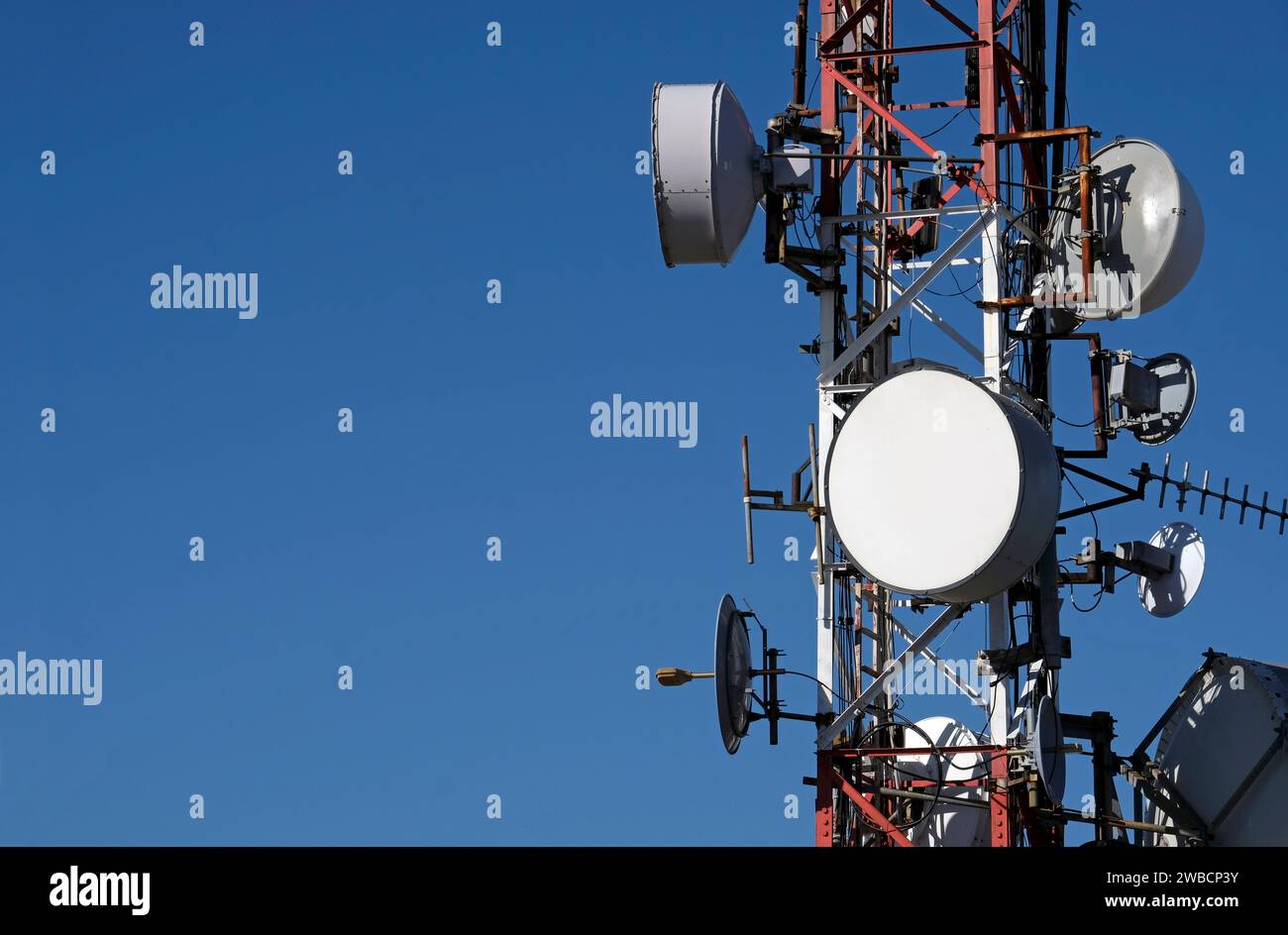 Telecommunication antenna with multiple satellite dishes against the blue sky Stock Photo