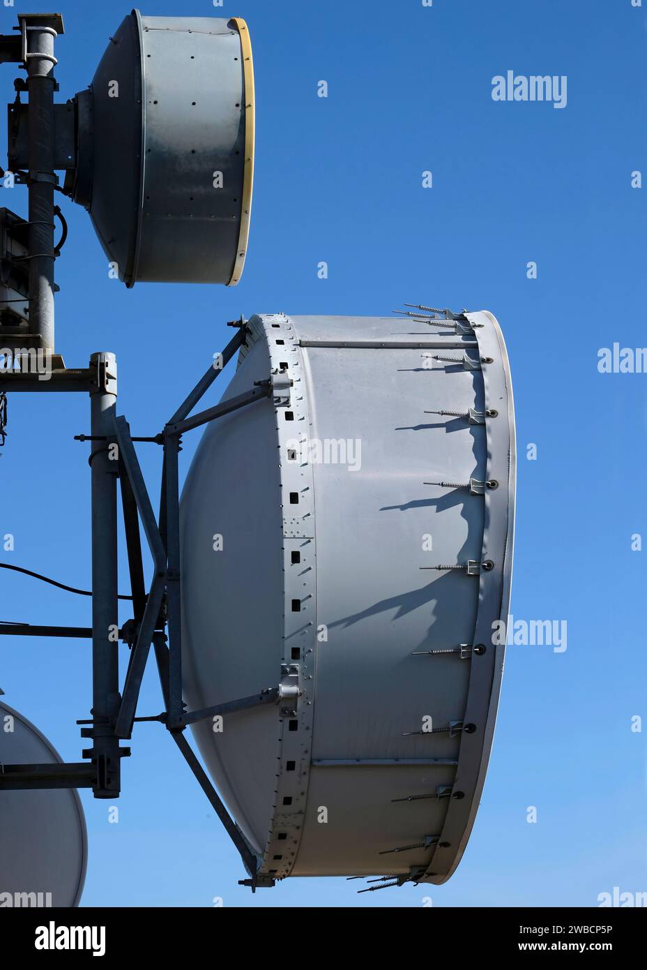 Telecommunication antenna with multiple satellite dishes against the blue sky Stock Photo