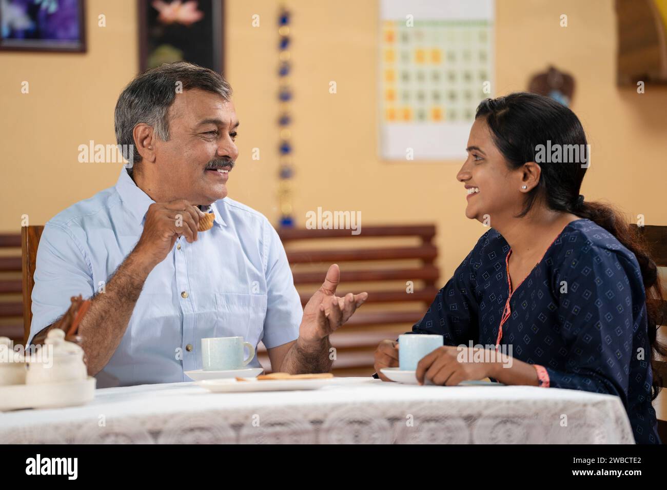 Happy father with daughter enjoys drinking morning coffee or tea at home by spending time together - concept of retirement lifestyle, family bonding Stock Photo