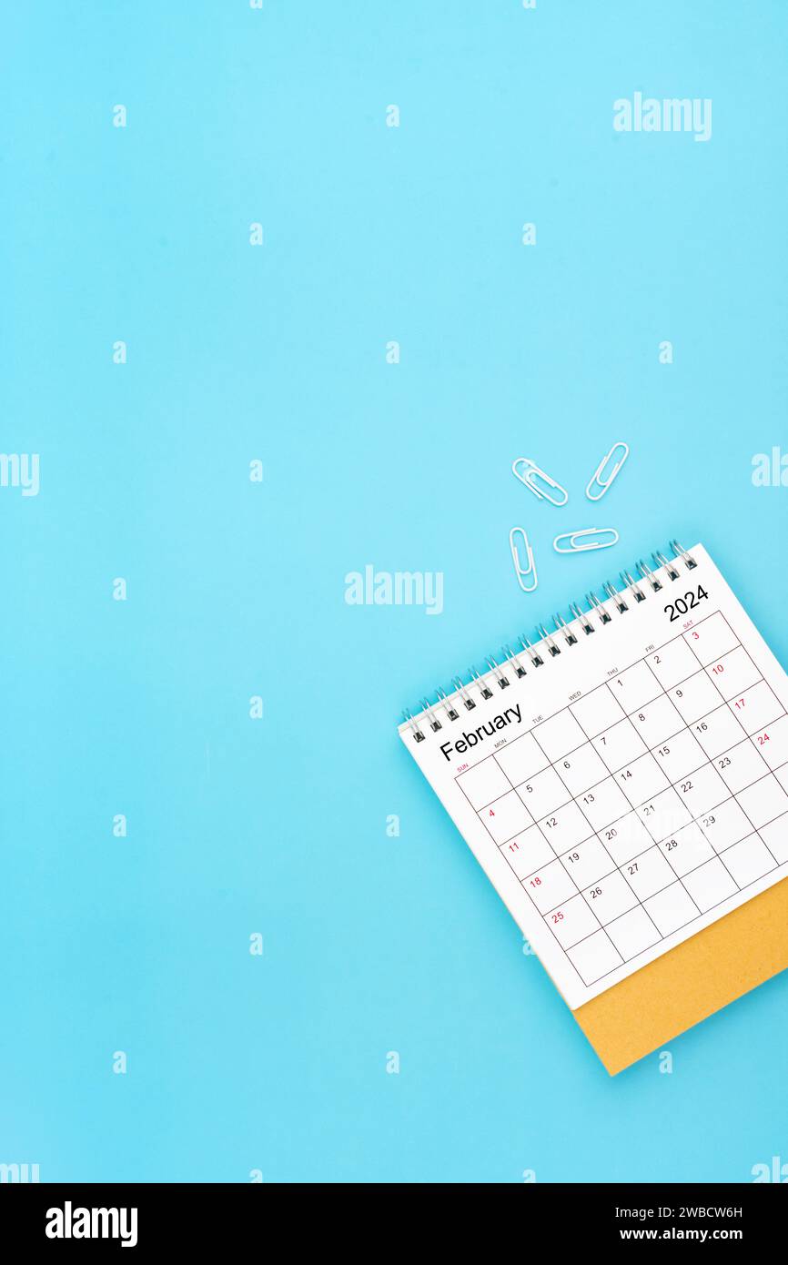 Desk calendar for February 2024 and white paper clip on a light blue ...