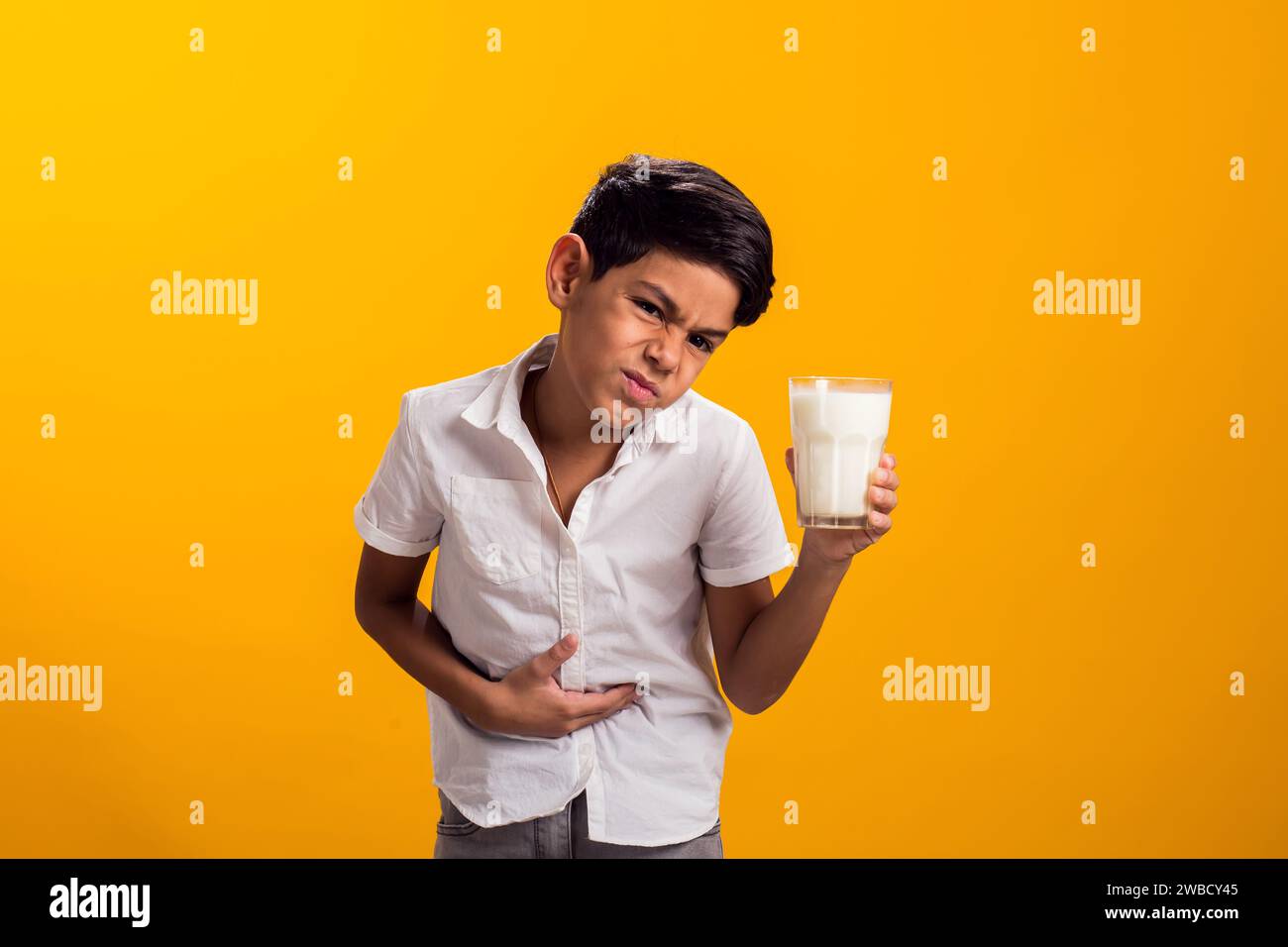 Boy with glass of milk feeling stomach pain. Dairy Intolerant person. Lactose intolerance, health care concept. Stock Photo