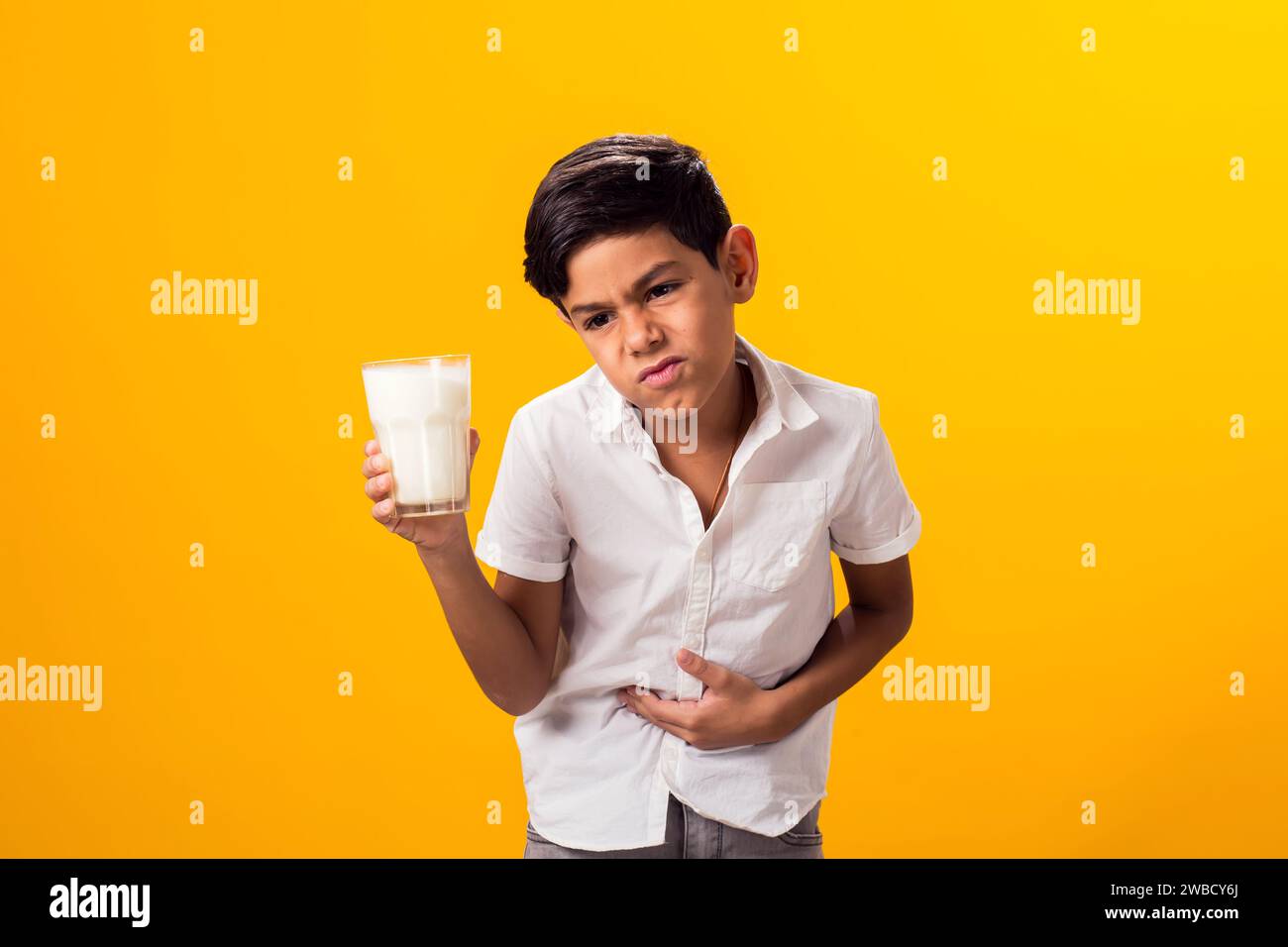 Boy with glass of milk feeling stomach pain. Dairy Intolerant person