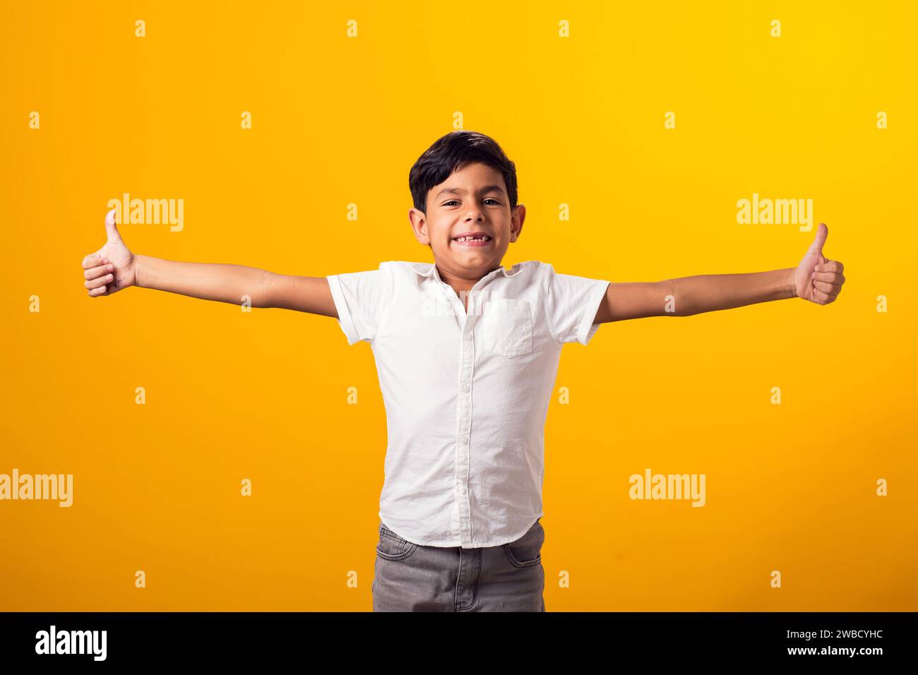 Portrait of kid boy showing thumb up gesture over yellow background ...