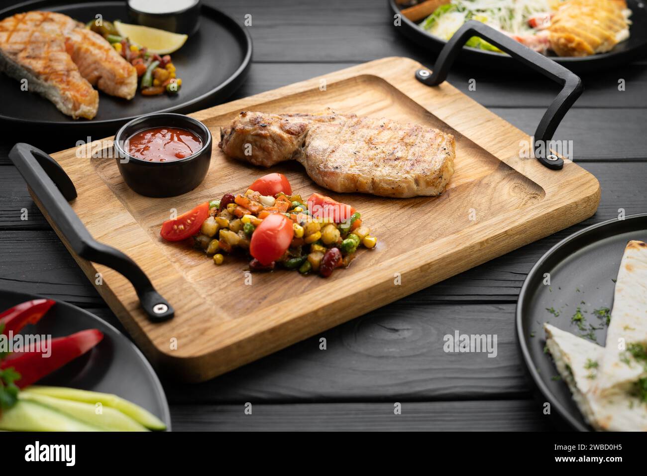 Grilled steak, fish, fillet and ribs served on a wooden table in a restaurant Stock Photo