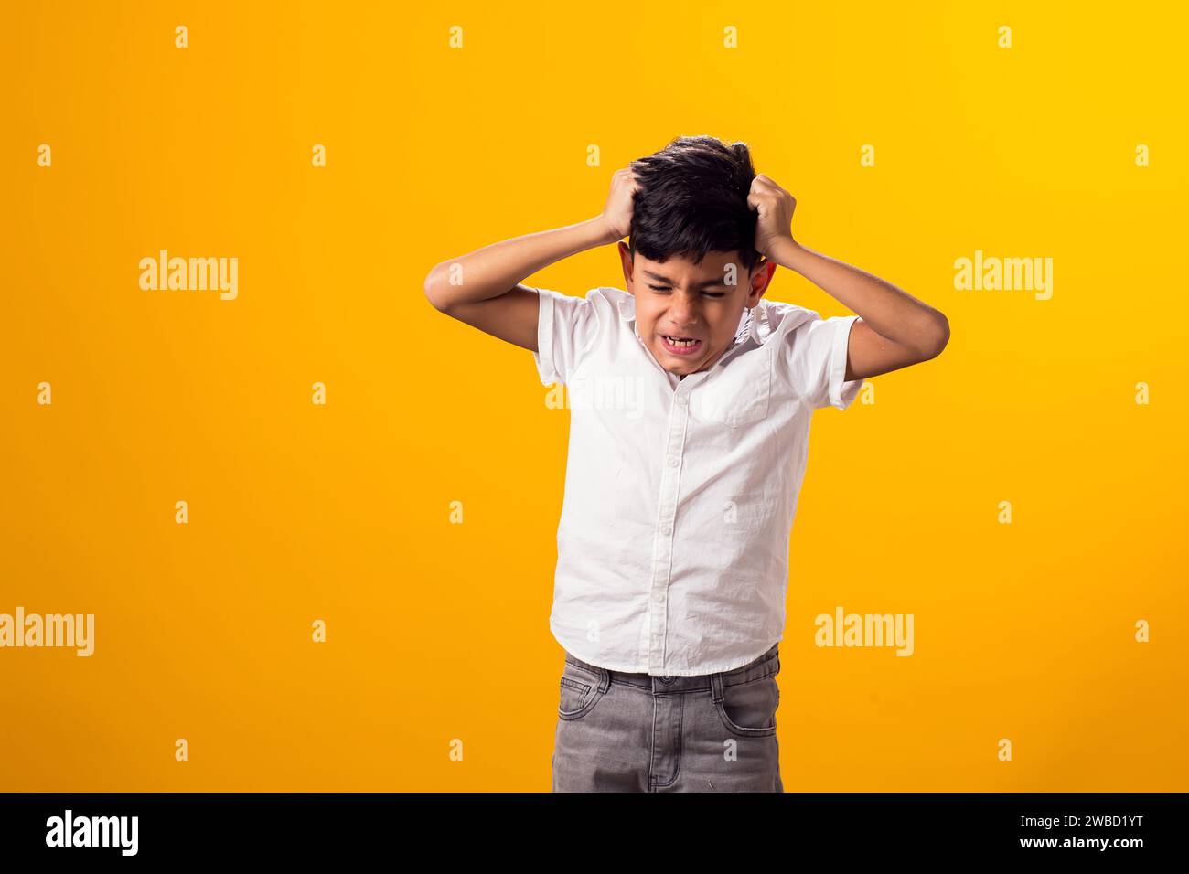 Portrait of angry kid boy over yellow background. Stress and aggression cocnept Stock Photo