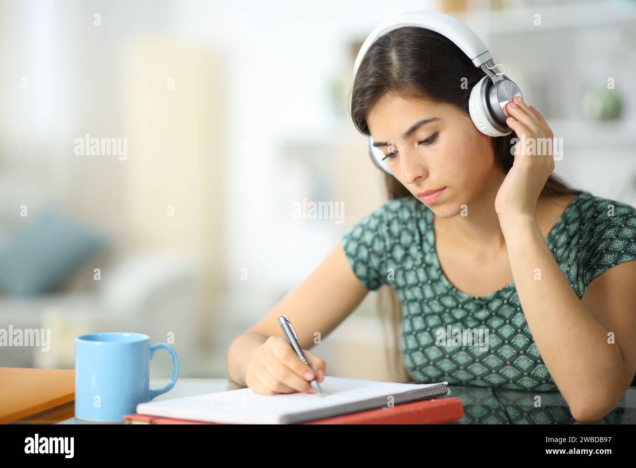 Student wearing headphone listening audio guide studying at home Stock Photo