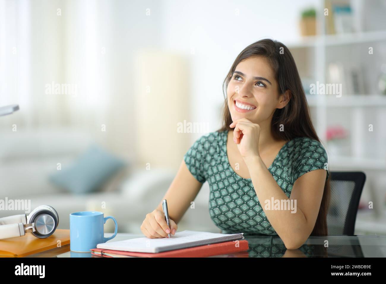 Happy student dreaming looking at side at home Stock Photo