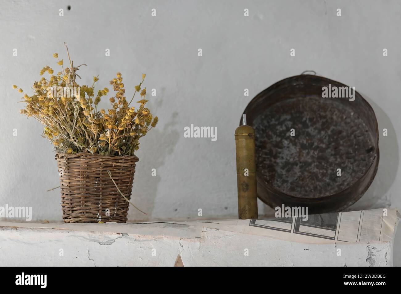 220 Set of home decoration in an early 1700s Ottoman house= ironwort flowers in wicker basket, brass coffee grinder and iron pan. Gjirokaster-Albania. Stock Photo