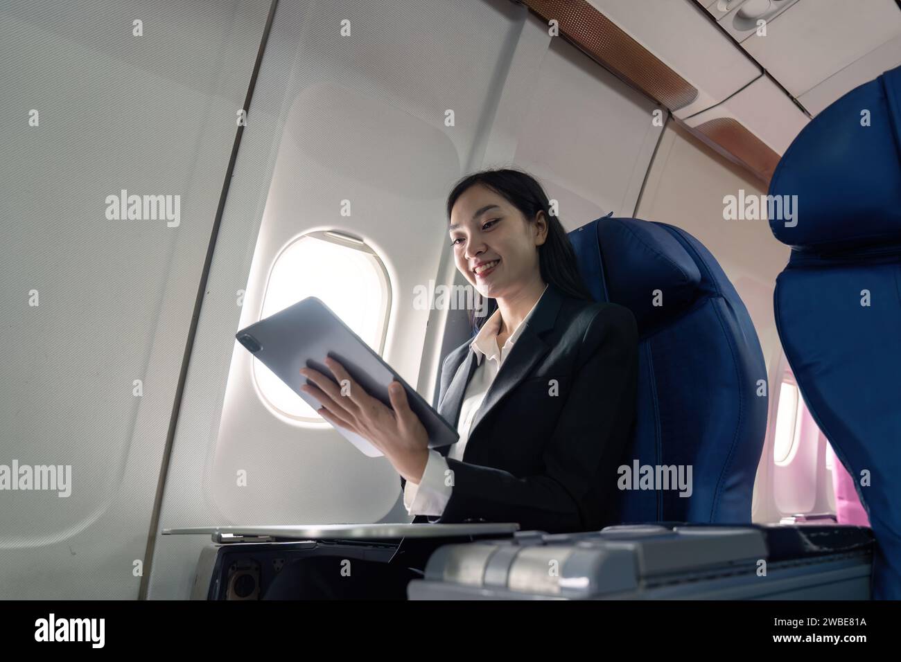 Successful young asian business woman sits in airplane cabin plane and working from anywhere. Flying at first class Stock Photo
