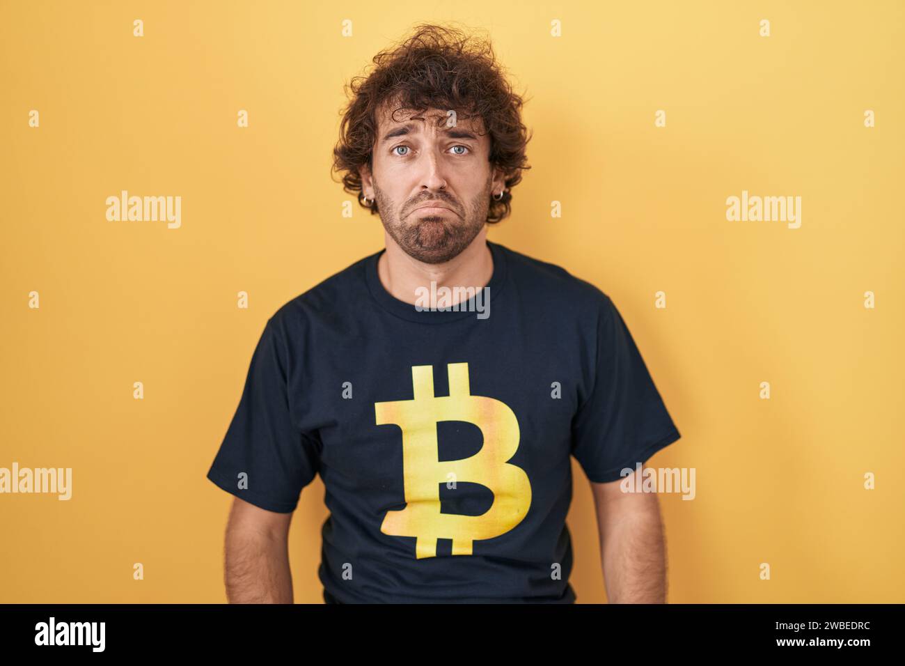 Hispanic young man wearing bitcoin t shirt depressed and worry for ...