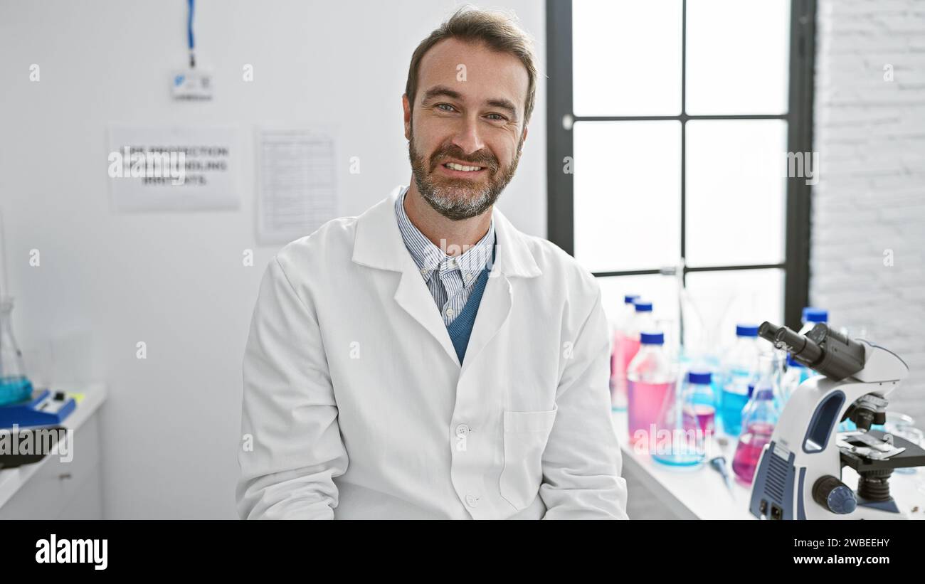 Smiling middle-aged hispanic man in lab coat indoors with microscope ...