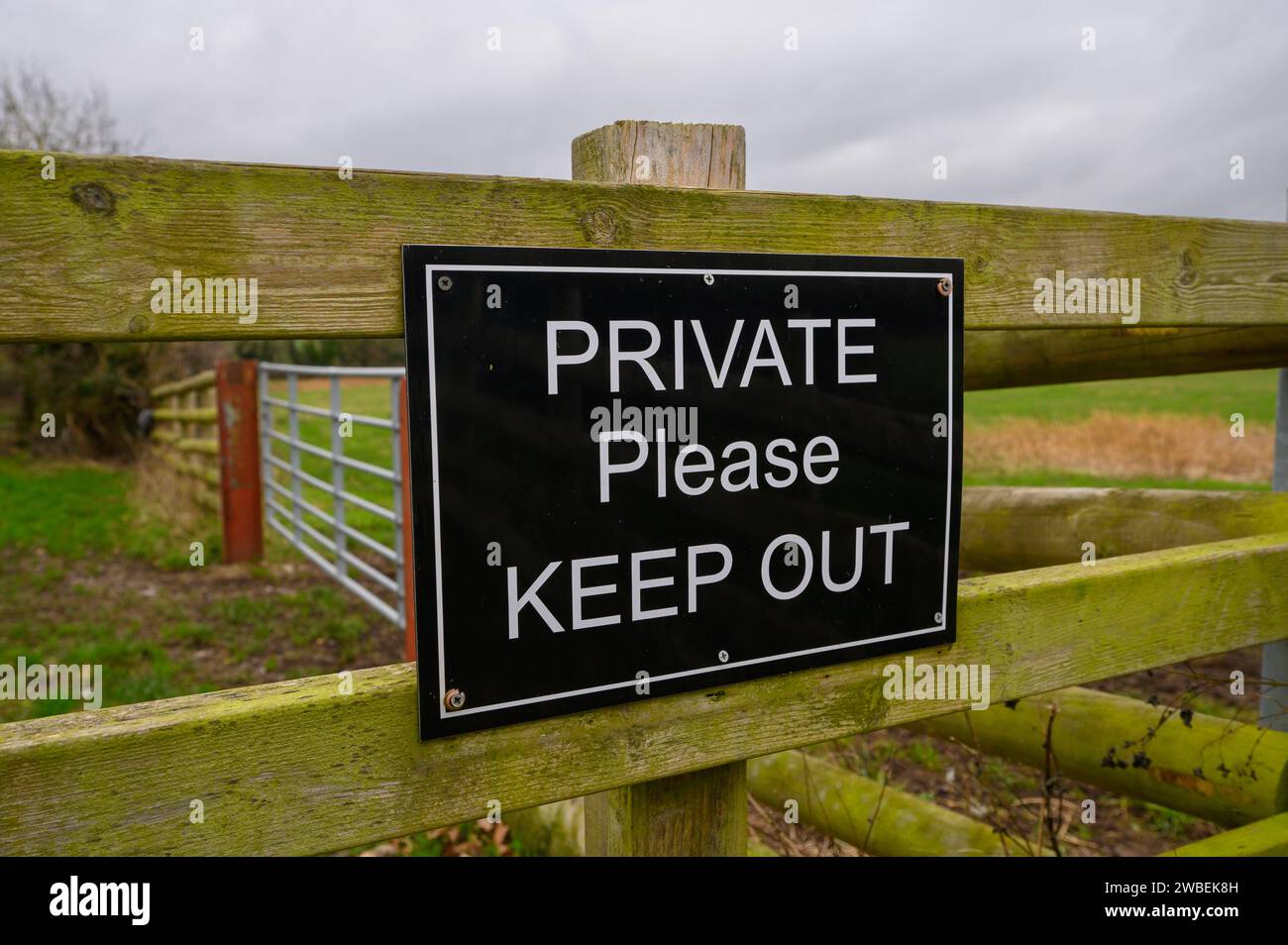 Black and white private please keep out sign on a wooden fence in a rural setting. Stock Photo
