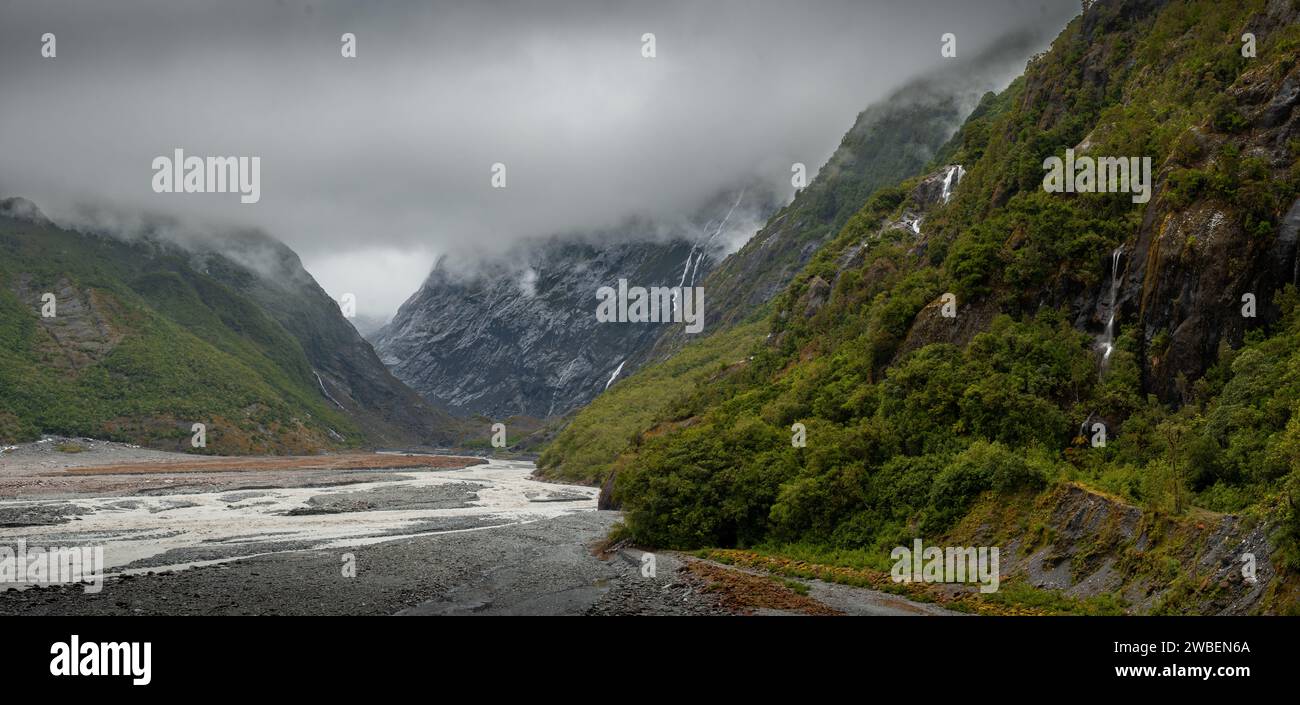 Moody view of Franz Josef glacial valley with low cloud and waterfalls Stock Photo