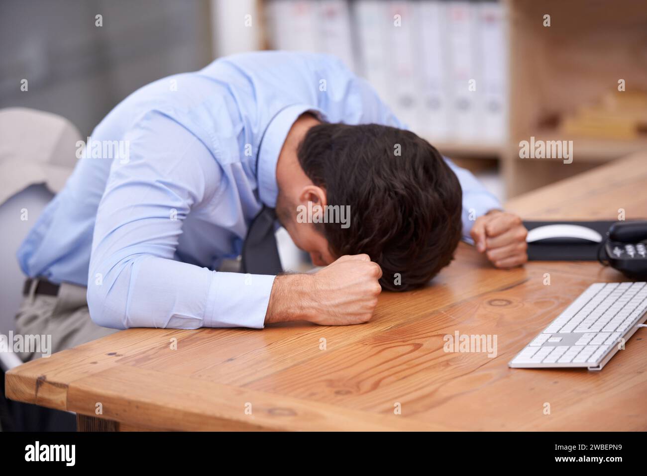 Business man, stress and resting on desk, burnout and mental health or overworked in workplace. Male professional, frustration and banging table in Stock Photo